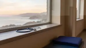 A hospital corridor window at dawn with a stethoscope resting on a sill