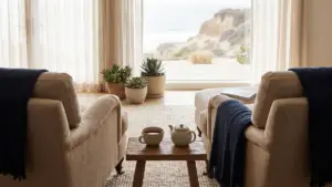 A cup of tea set down on a low table between two empty armchairs