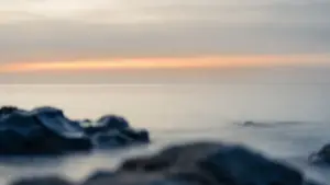 A dawn horizon over still water with a single band of warm light