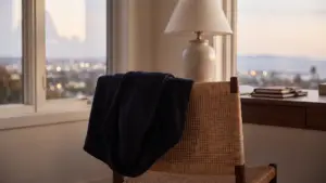 A tailored jacket hung on the back of a chair in a quiet home office at dusk
